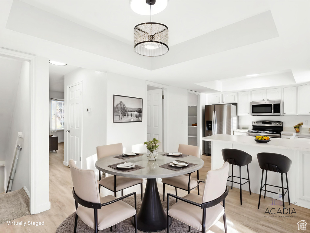Dining area with a raised ceiling and light wood finished floors