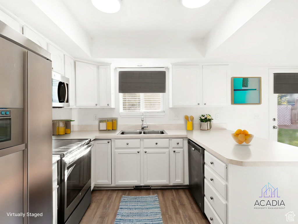 Kitchen featuring stainless steel appliances, a peninsula, light countertops, and white cabinetry