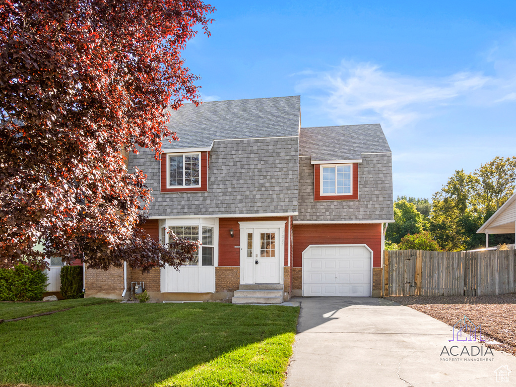 Dutch colonial featuring roof with shingles, driveway, brick siding, and an attached garage