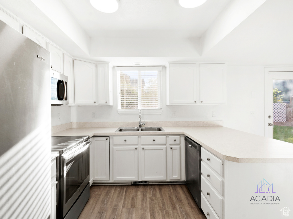 Kitchen with stainless steel appliances, a peninsula, dark wood-style floors, and plenty of natural light