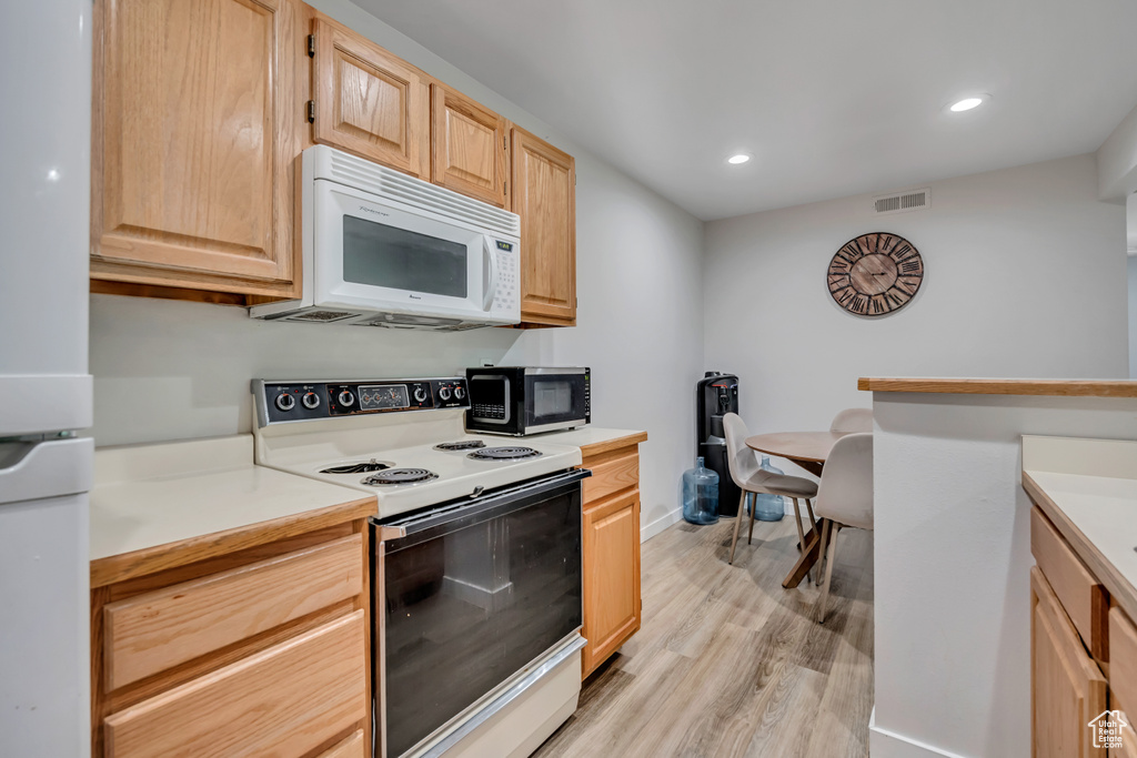 Kitchen featuring white appliances, light brown cabinetry, light wood-style flooring, light countertops, and recessed lighting