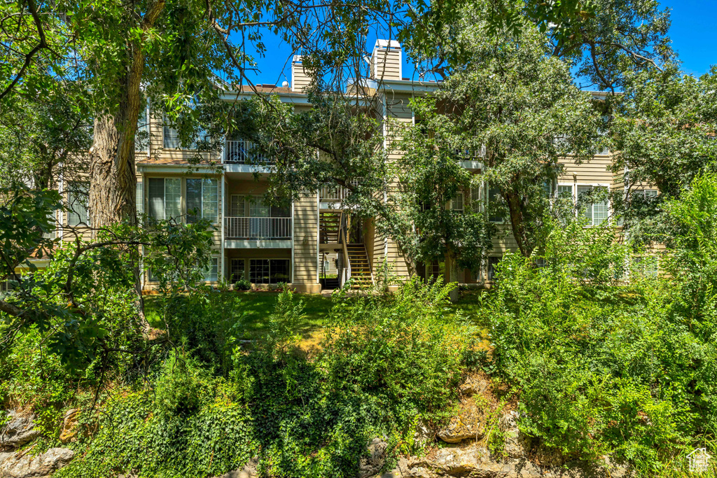 Back of house with a chimney, stairs, and a balcony