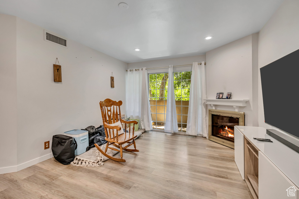Sitting room with a glass covered fireplace, light wood-style flooring, and recessed lighting