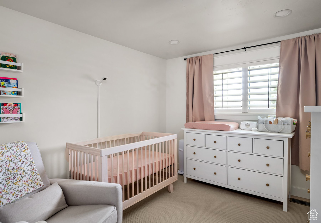 Bedroom with light colored carpet, a nursery area, and recessed lighting