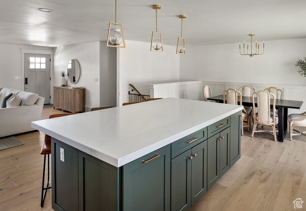 Kitchen featuring a kitchen island, open floor plan, light wood-type flooring, and a chandelier