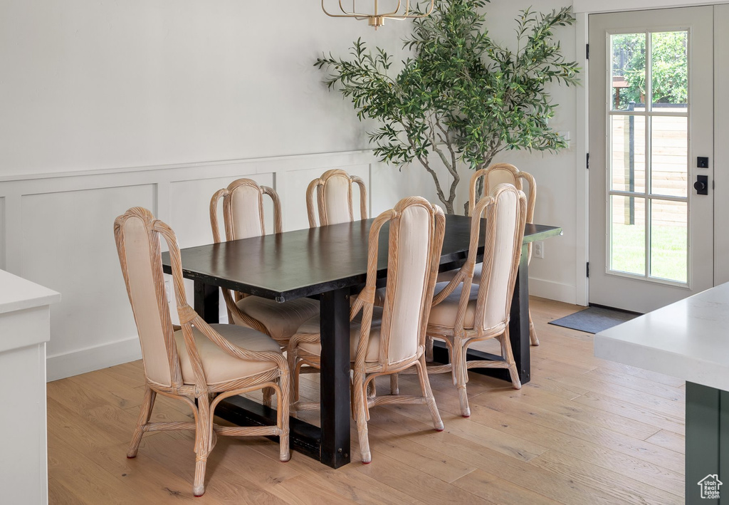 Dining space with a wainscoted wall, plenty of natural light, and light wood-style flooring