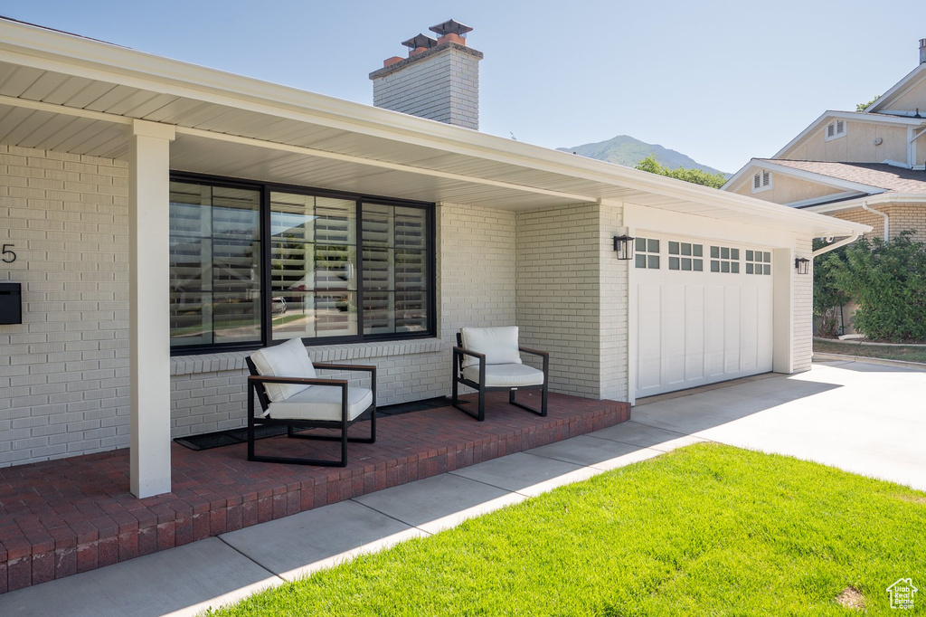 View of front of property with driveway, brick siding, a chimney, a mountain view, and a garage
