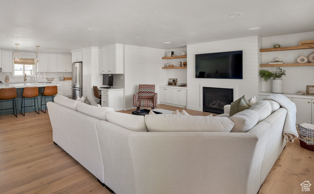 Living room with light wood-type flooring, a glass covered fireplace, and recessed lighting