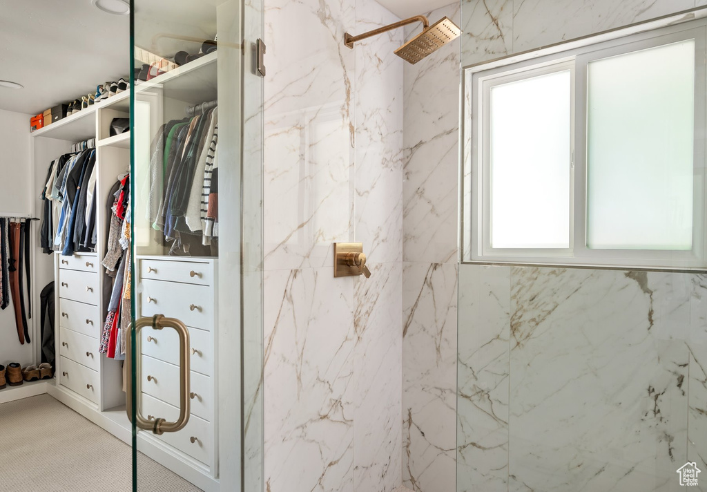 Full bathroom with a marble finish shower and a walk in closet