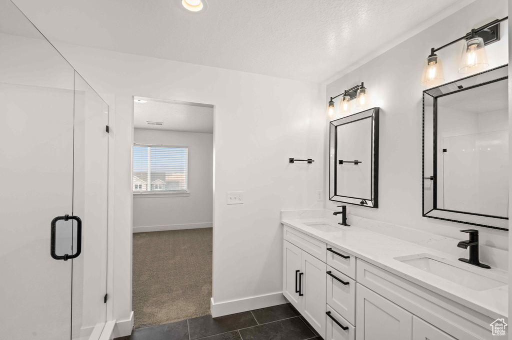 Bathroom with double vanity, tile patterned floors, and a shower with door