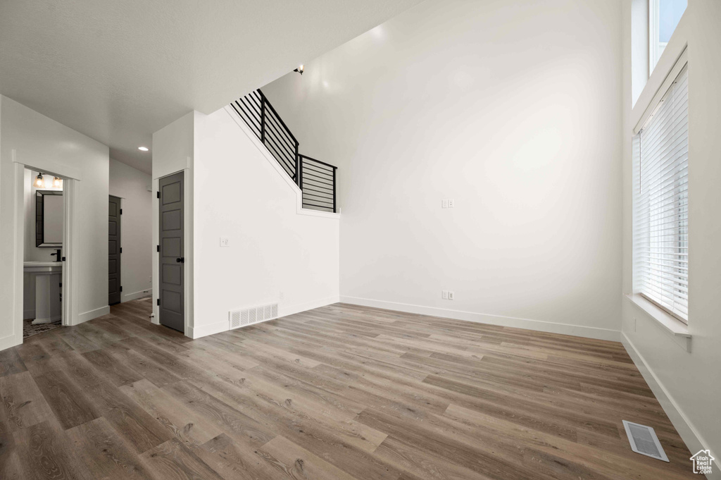 Unfurnished living room featuring plenty of natural light, wood finished floors, stairway, and recessed lighting