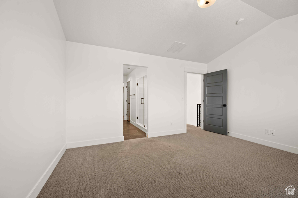 Carpeted empty room with lofted ceiling and baseboards