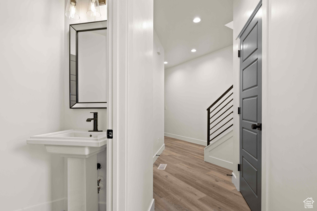 Hall with wood finished floors, stairway, and recessed lighting