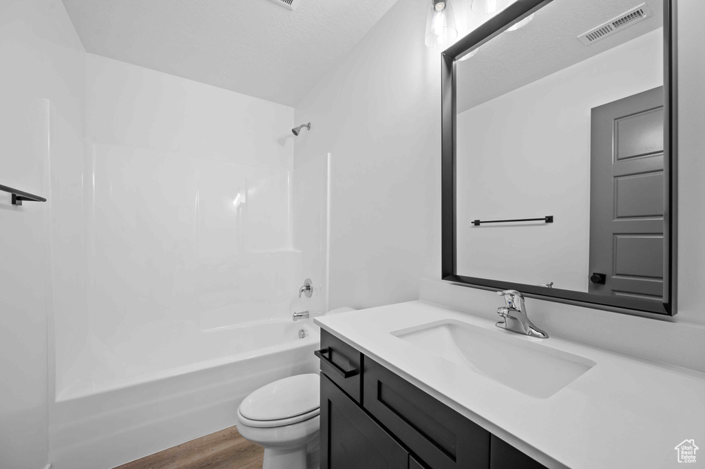 Bathroom with vanity, washtub / shower combination, and wood finished floors