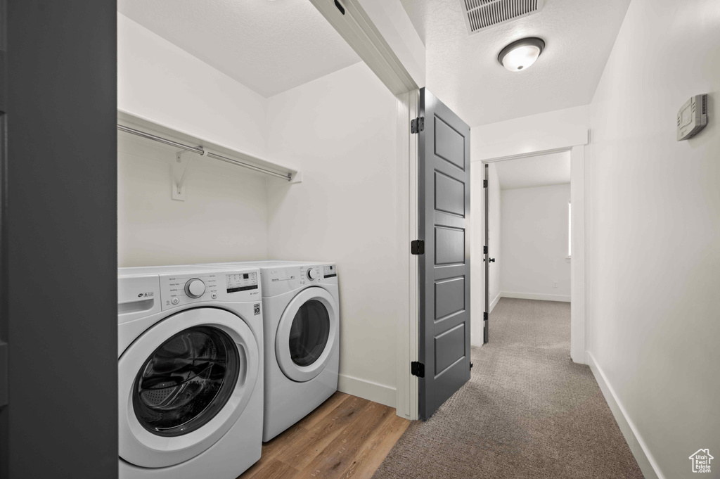 Washroom with washing machine and clothes dryer and wood finished floors