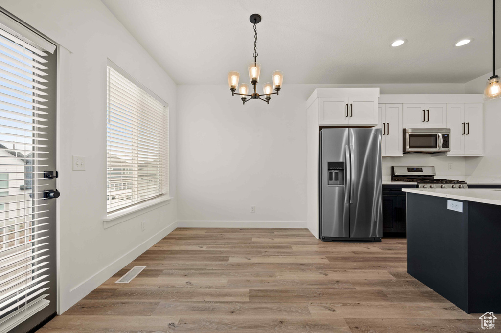 Kitchen featuring appliances with stainless steel finishes, a chandelier, white cabinetry, decorative light fixtures, and recessed lighting