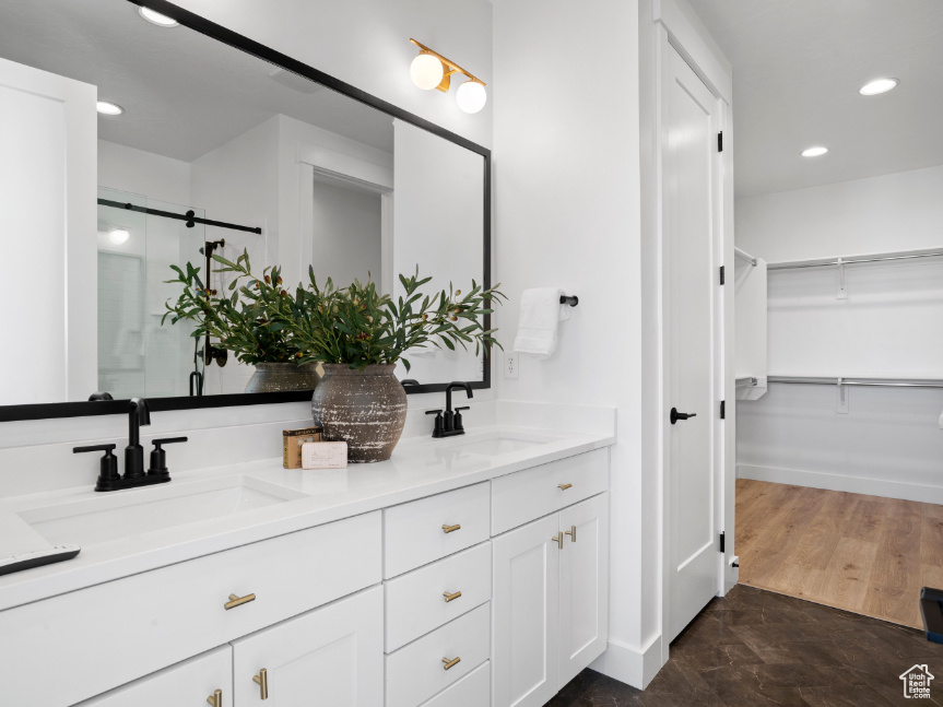 Bathroom with double vanity, a walk in closet, a stall shower, and recessed lighting