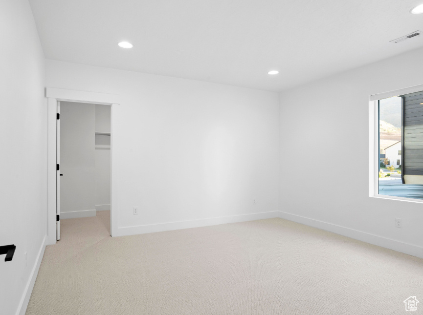 Empty room with light colored carpet and recessed lighting