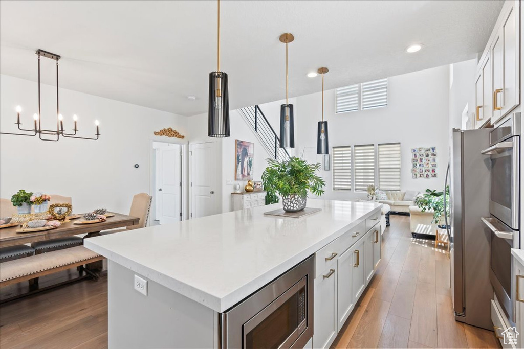 Kitchen featuring appliances with stainless steel finishes, light wood-style flooring, a kitchen island, light countertops, and recessed lighting