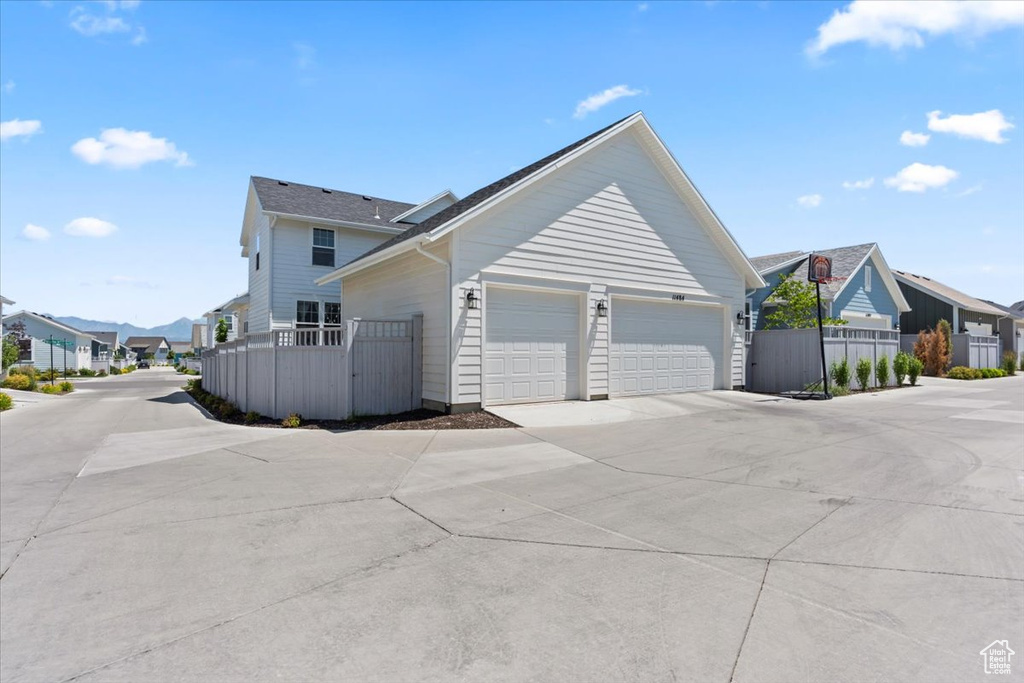 View of side of property featuring a residential view, driveway, and a garage