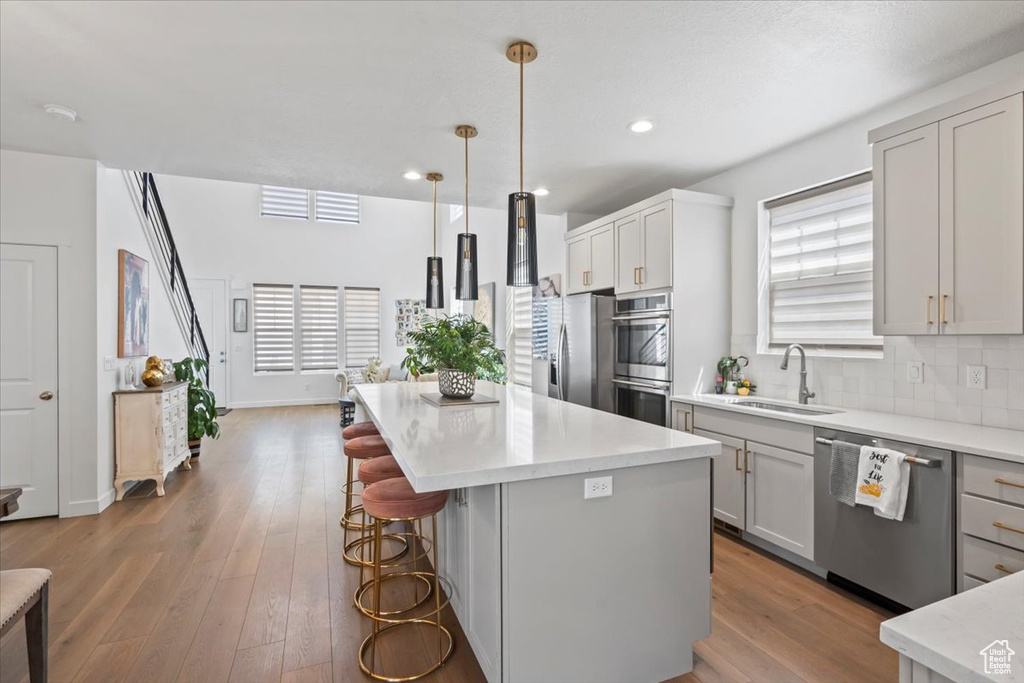 Kitchen with appliances with stainless steel finishes, decorative backsplash, a kitchen bar, a center island, and recessed lighting