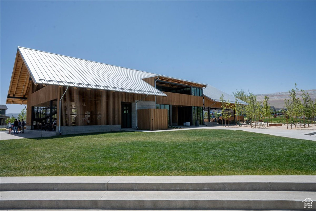Rear view of property featuring a standing seam roof, a lawn, and a metal roof