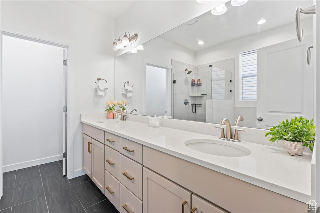 Bathroom with double vanity, a shower stall, and recessed lighting