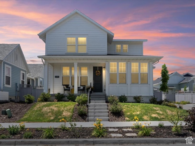 Traditional-style house featuring board and batten siding, a porch, stairs, and a front lawn
