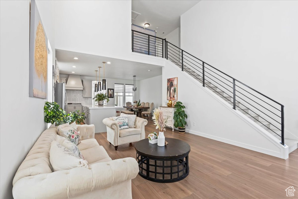 Living room with light wood-style floors, stairway, and a high ceiling
