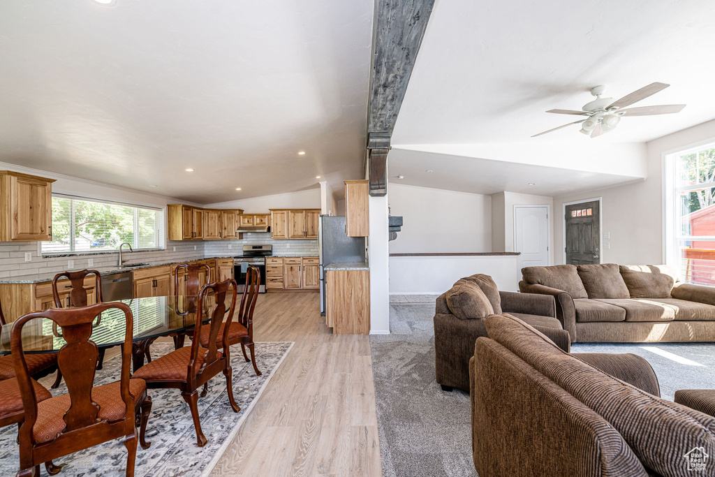 Living room with light wood finished floors, a ceiling fan, vaulted ceiling, and recessed lighting