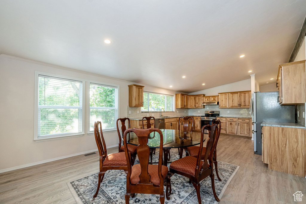 Dining area with light wood-style flooring, lofted ceiling, recessed lighting, and ornamental molding