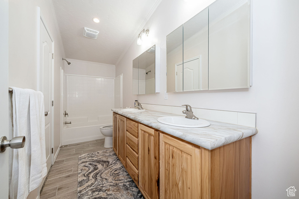 Bathroom featuring double vanity, wood finished floors, and shower / tub combination