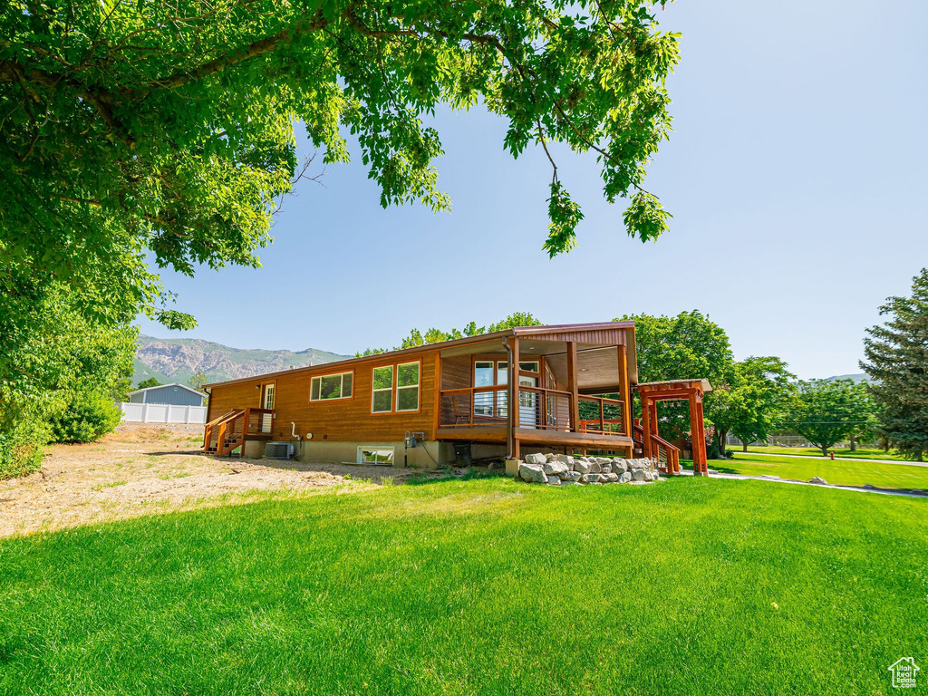 Rear view of house featuring a lawn and a deck with mountain view