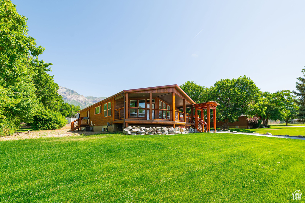 Rear view of house featuring a yard, a mountain view, and stairway