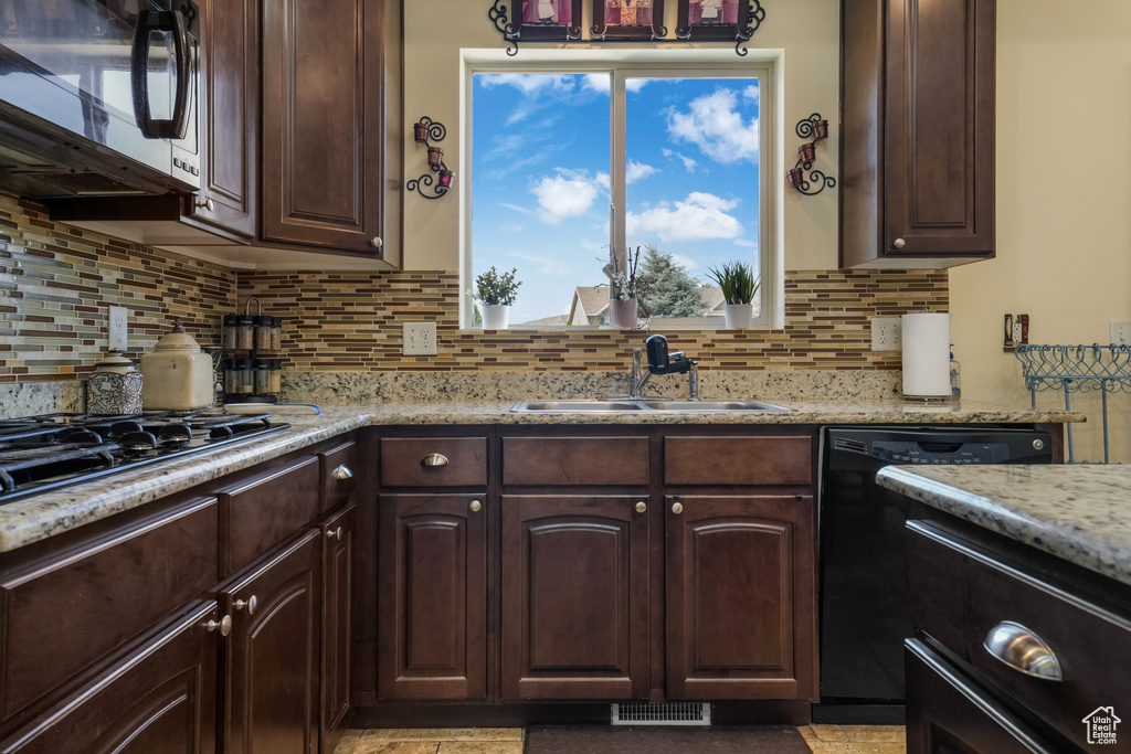 Kitchen featuring black appliances, dark brown cabinets, tasteful backsplash, and light stone countertops