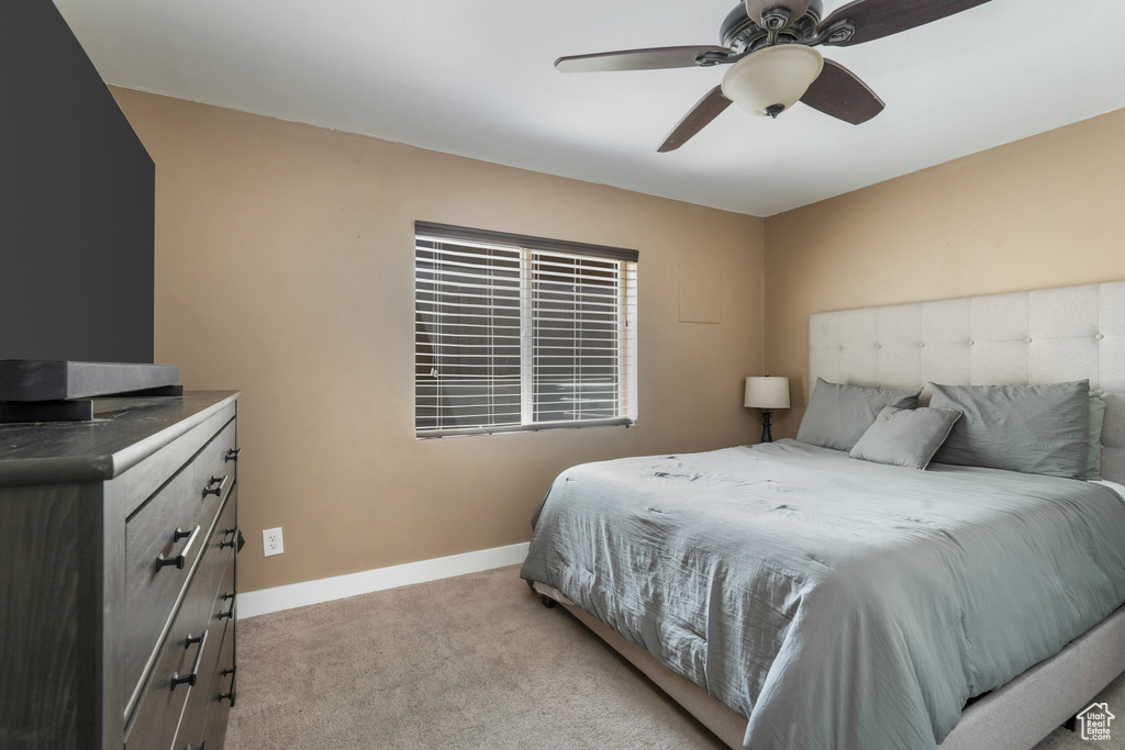 Bedroom with light colored carpet and a ceiling fan