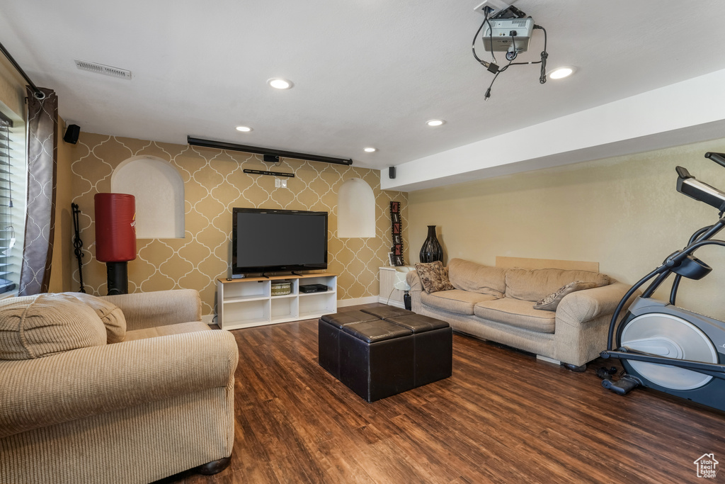 Living room with wallpapered walls, wood finished floors, and recessed lighting