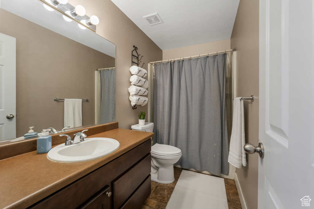 Full bathroom featuring vanity, curtained shower, and stone finish floors