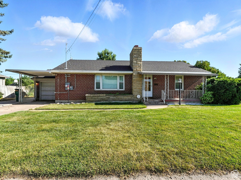 Single story home with concrete driveway, brick siding, a chimney, an attached garage, and a carport