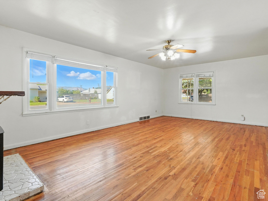 Unfurnished living room featuring light wood-style floors and a ceiling fan
