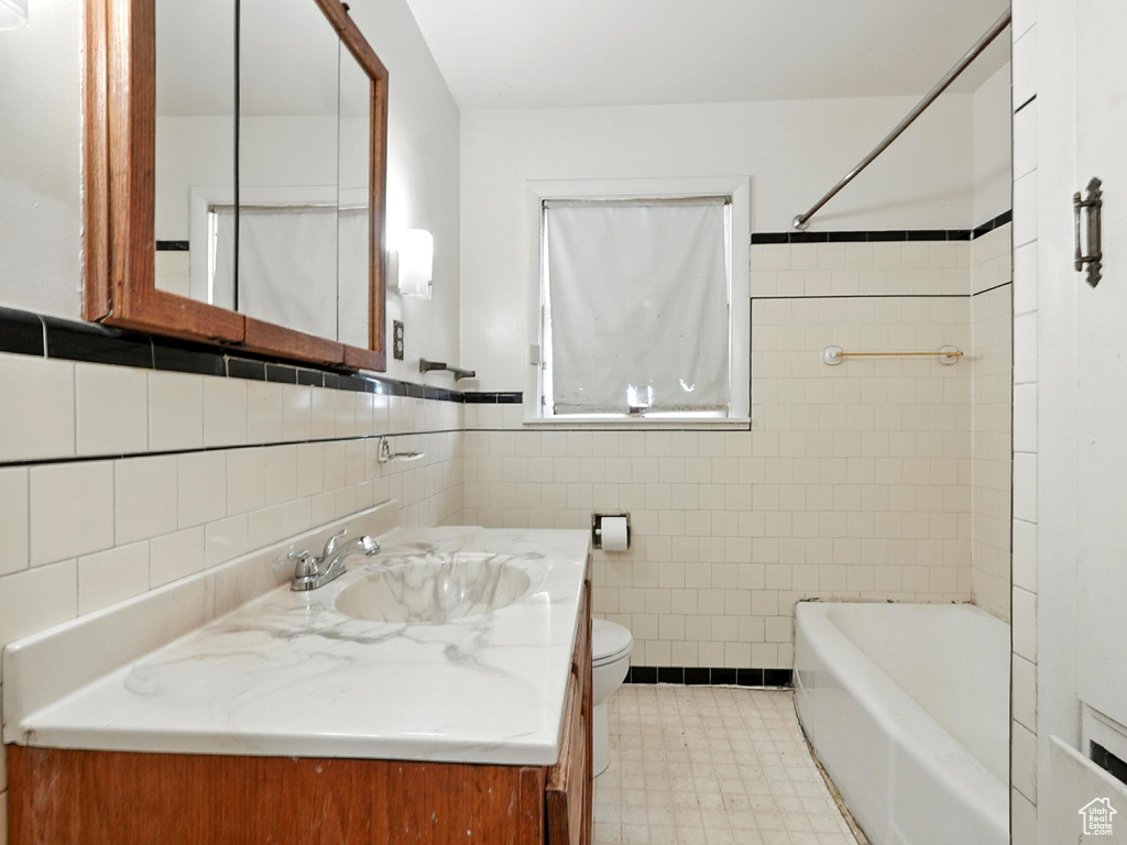 Bathroom featuring tile walls, tile patterned floors, vanity, and shower / washtub combination