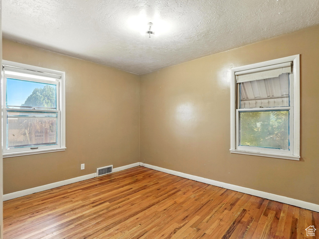 Empty room with light wood finished floors and a textured ceiling