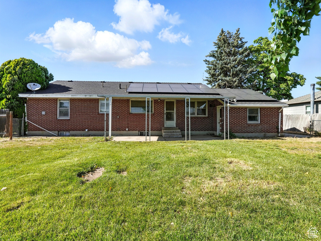 Back of property with entry steps, a patio, a fenced backyard, and solar panels