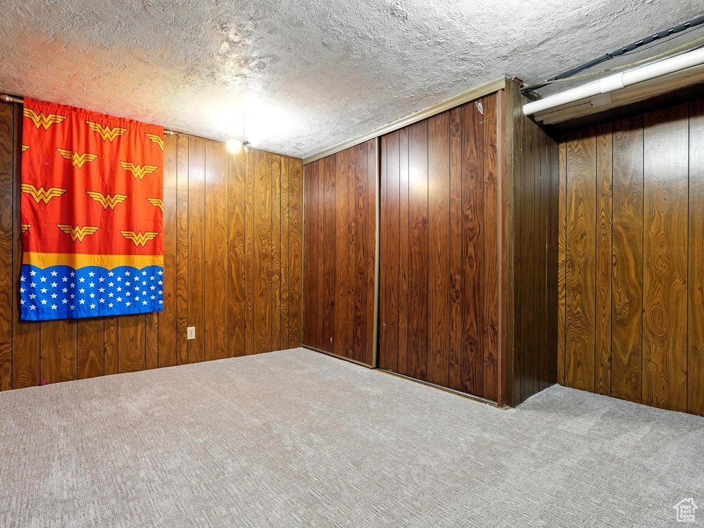 Carpeted empty room with wood walls and a textured ceiling