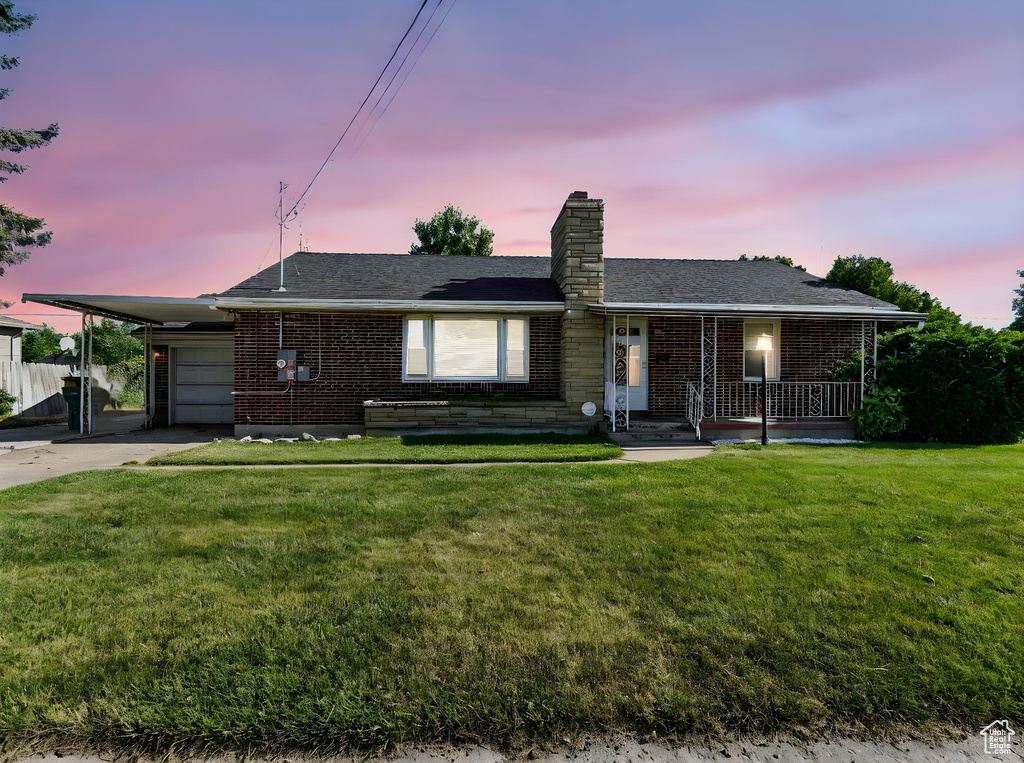 Ranch-style home with brick siding, a chimney, covered porch, and driveway