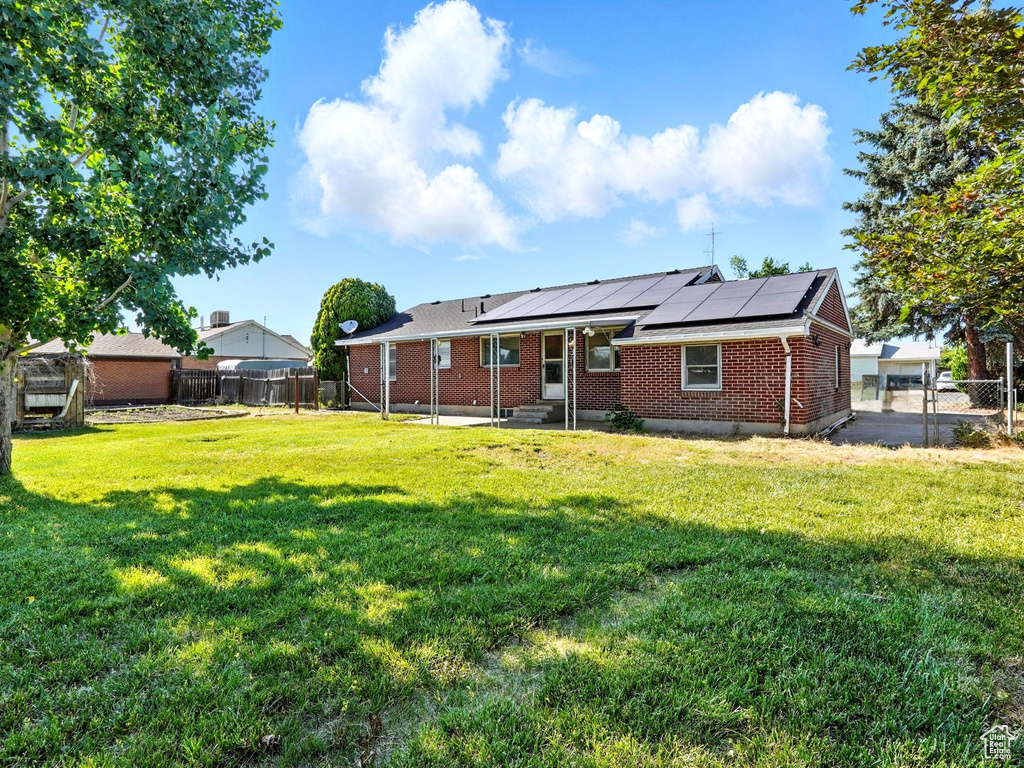 Back of property featuring brick siding, roof mounted solar panels, a fenced backyard, and a patio area