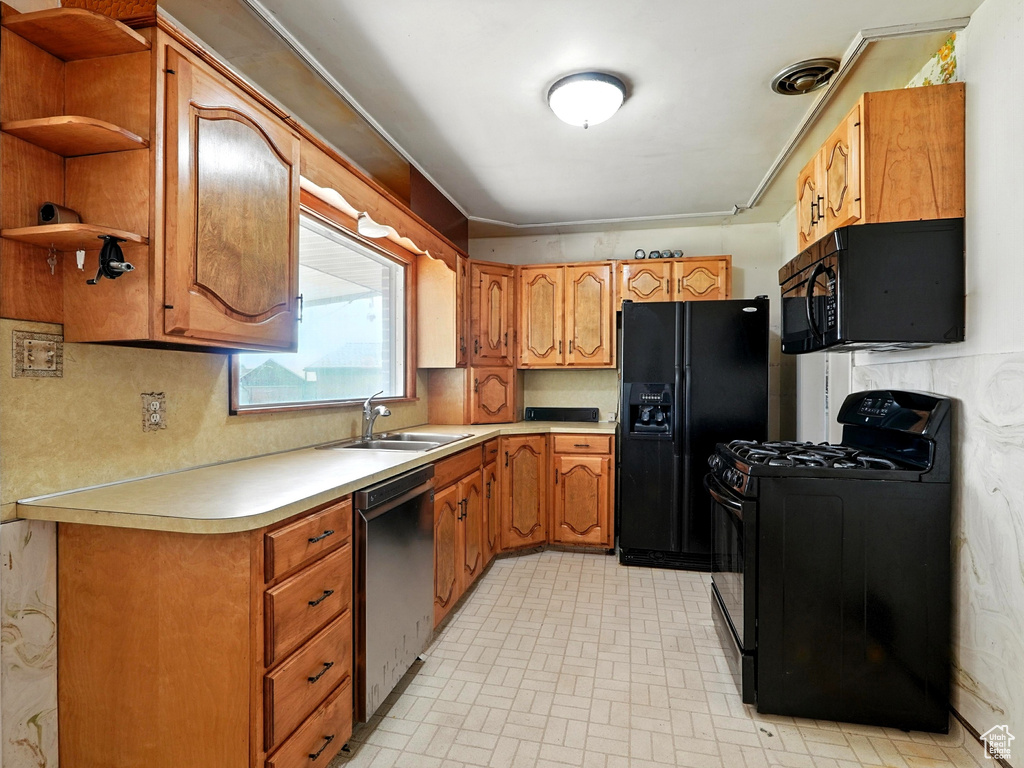Kitchen featuring black appliances, light countertops, brown cabinets, open shelves, and brick patterned floors
