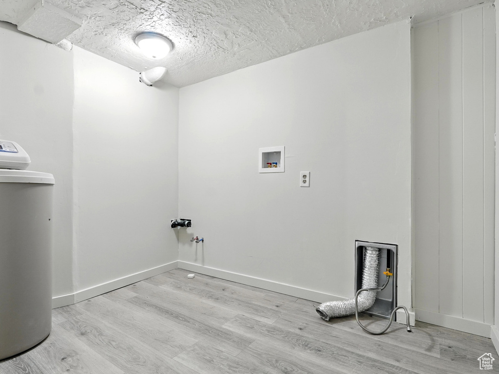 Washroom with light wood-style floors, a textured ceiling, and washer hookup