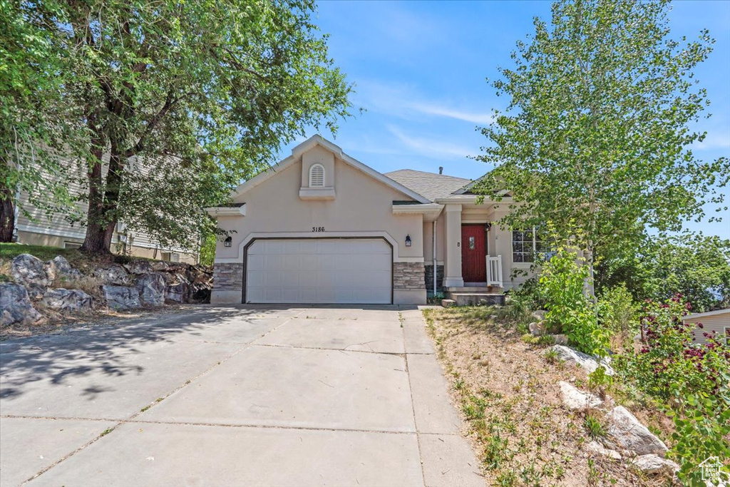 View of front of property with stucco siding, an attached garage, concrete driveway, and stone siding