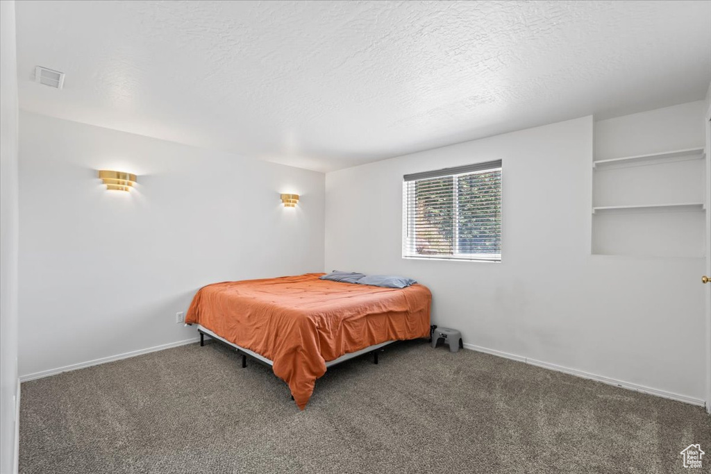 Carpeted bedroom featuring baseboards and a textured ceiling